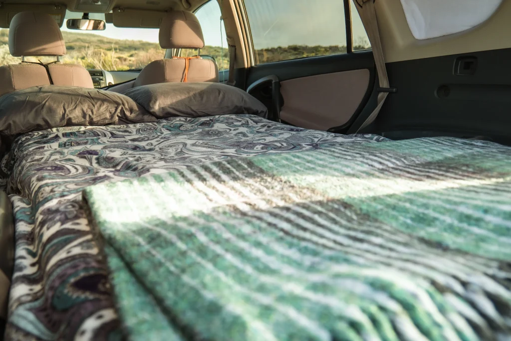 A made bed with two pillows and blankets in the back of the car.